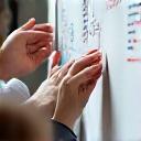 Close-up of hands brainstorming on a whiteboard.